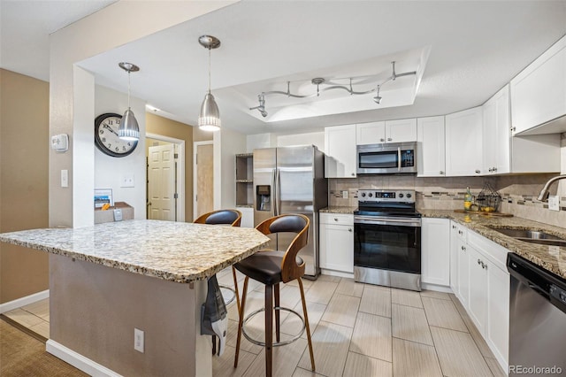 kitchen with sink, stainless steel appliances, a breakfast bar area, decorative backsplash, and white cabinets