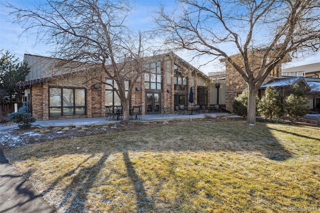 back of property featuring a lawn, french doors, and a patio