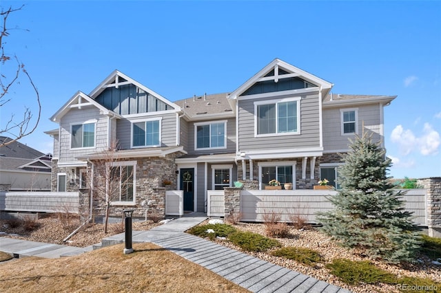 view of front of property featuring stone siding, board and batten siding, and a fenced front yard