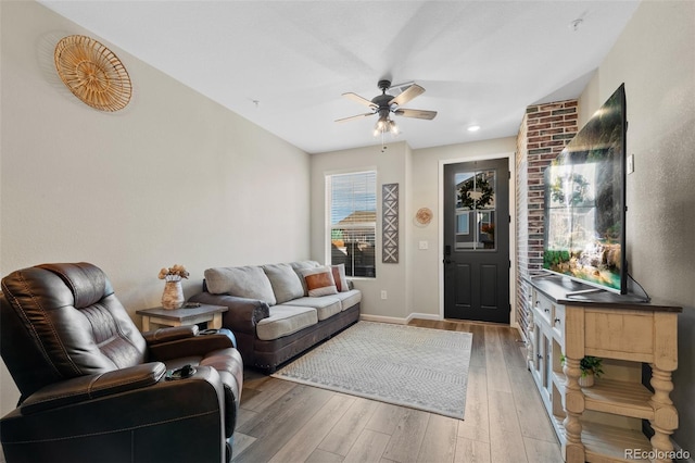 living room featuring light wood-type flooring, ceiling fan, and baseboards