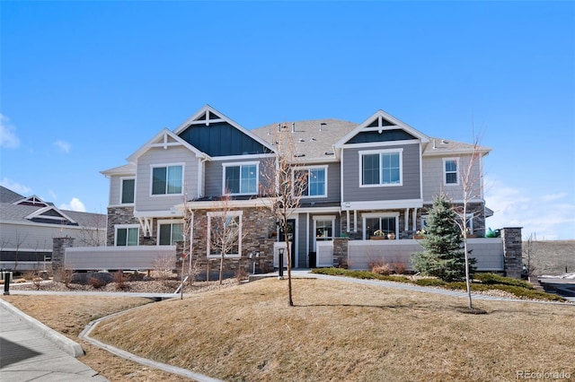 view of front of property with board and batten siding, stone siding, and fence