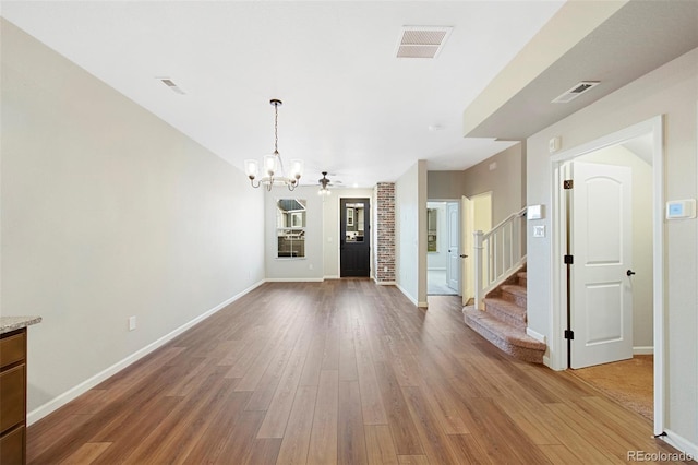 unfurnished dining area featuring visible vents, wood finished floors, and a chandelier