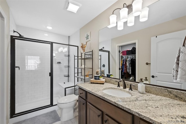 bathroom featuring vanity, toilet, a walk in closet, a shower stall, and a notable chandelier