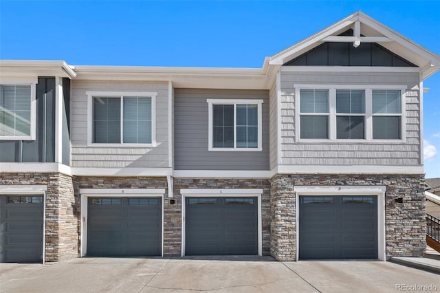 view of front of property featuring a garage, board and batten siding, driveway, and stone siding