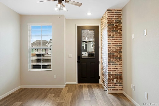 foyer entrance featuring baseboards, a ceiling fan, and light wood finished floors