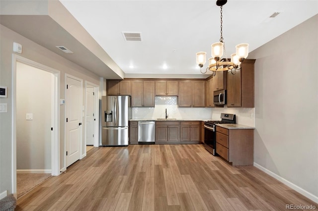kitchen featuring appliances with stainless steel finishes, an inviting chandelier, light wood-style flooring, baseboards, and visible vents