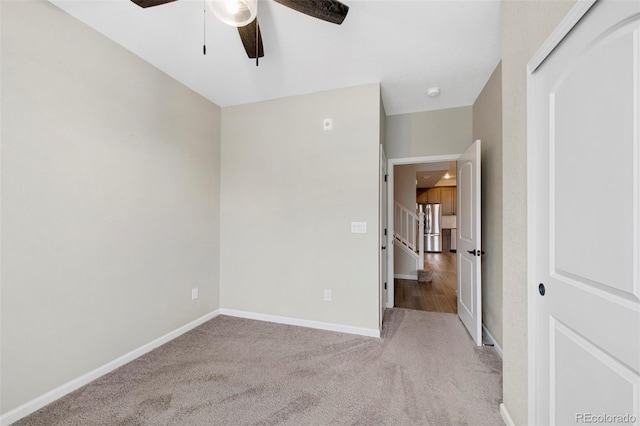 unfurnished bedroom featuring baseboards, freestanding refrigerator, carpet, and a ceiling fan