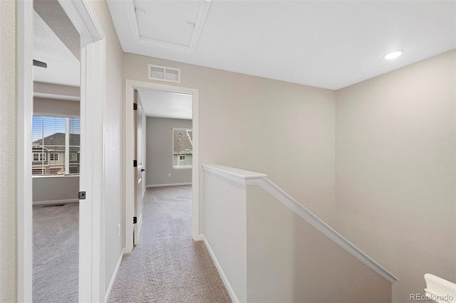 corridor featuring attic access, visible vents, baseboards, an upstairs landing, and light carpet