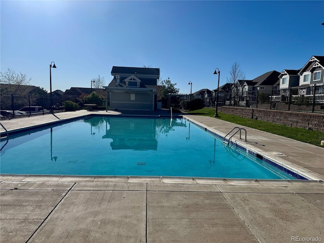 pool featuring a patio, fence, and a residential view