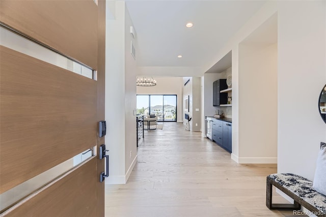 hall featuring an inviting chandelier and light wood-type flooring