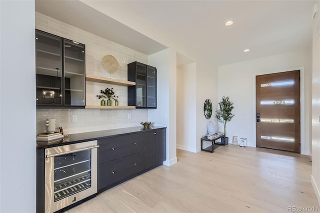 bar featuring wine cooler, light wood-type flooring, and decorative backsplash