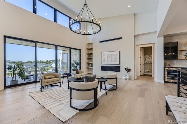 living room featuring wine cooler, light hardwood / wood-style floors, and a notable chandelier