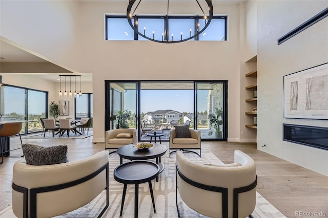 living room with a notable chandelier, light hardwood / wood-style flooring, and built in features