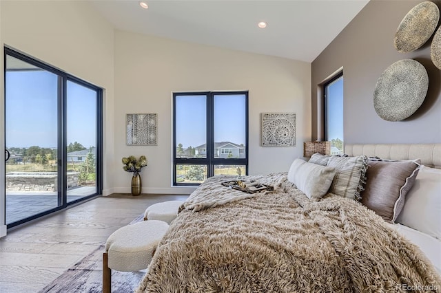 bedroom with lofted ceiling, access to outside, and light hardwood / wood-style floors