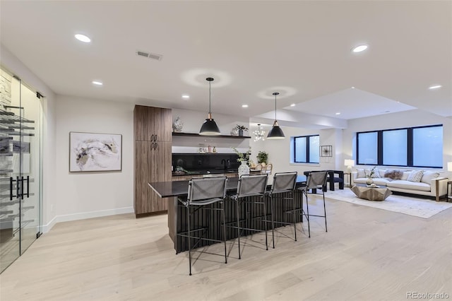 kitchen featuring a kitchen island, pendant lighting, a kitchen bar, and light hardwood / wood-style flooring