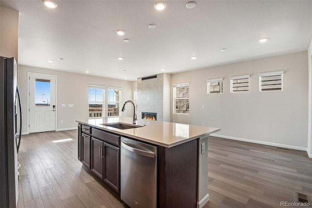 kitchen featuring dark brown cabinetry, a sink, light countertops, appliances with stainless steel finishes, and an island with sink