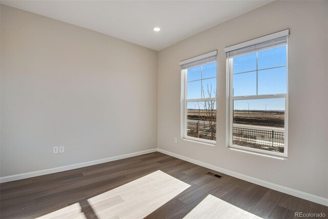 empty room featuring dark wood-style floors, baseboards, visible vents, and recessed lighting