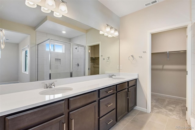 full bath featuring double vanity, a spacious closet, visible vents, and a sink