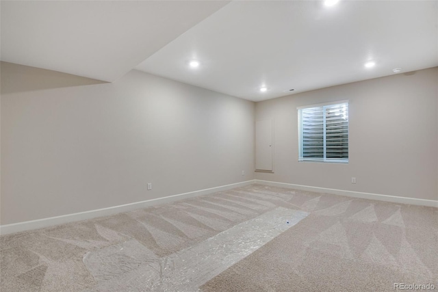 empty room featuring recessed lighting, light colored carpet, and baseboards