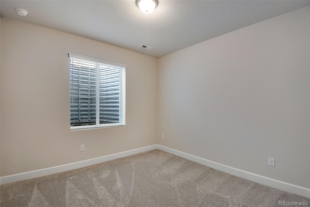 carpeted spare room featuring visible vents and baseboards