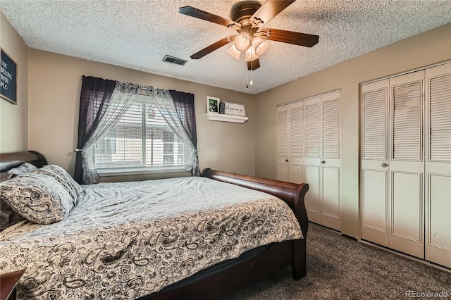 bedroom with multiple closets, ceiling fan, carpet flooring, and a textured ceiling