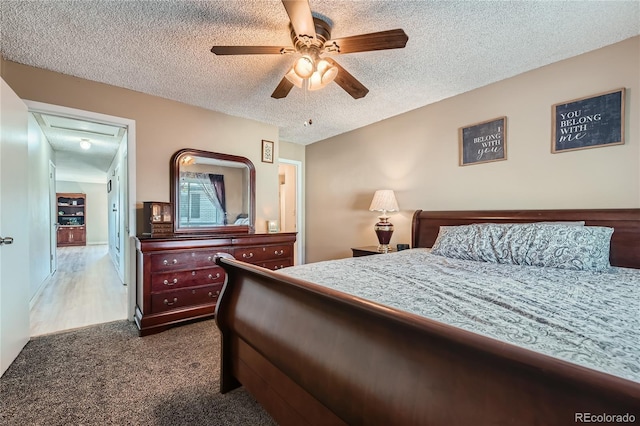 carpeted bedroom featuring ceiling fan and a textured ceiling