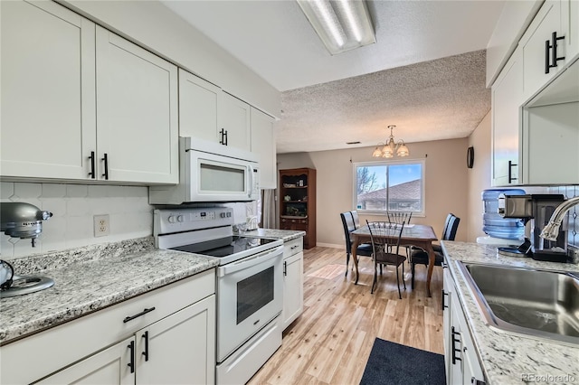 kitchen with white cabinetry, white appliances, light hardwood / wood-style floors, and sink