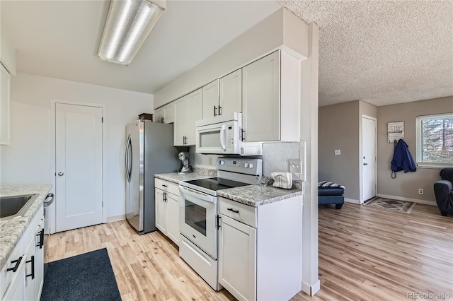 kitchen featuring white cabinetry, white appliances, and light stone countertops