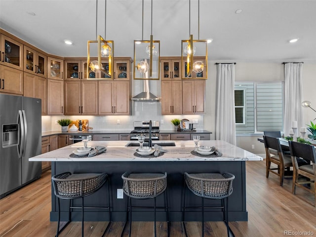 1787 W 166th Ave, Broomfield, CO 80023 - kitchen with appliances with stainless steel finishes, light wood-type flooring, a kitchen bar, light stone counters, and decorative light fixtures