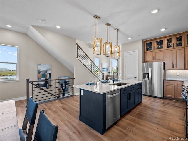1787 W 166th Ave, Broomfield, CO 80023 - kitchen featuring appliances with stainless steel finishes, a kitchen island with sink, light countertops, wood finished floors, and recessed lighting