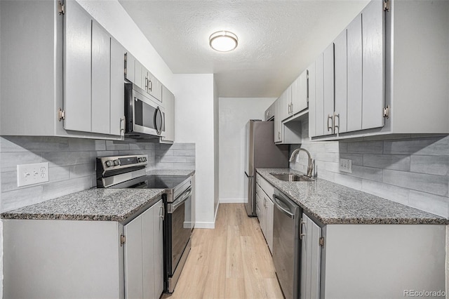 16259 W 10th Ave Unit K-3, Golden, CO 80401 - kitchen featuring stainless steel appliances, tasteful backsplash, light wood-style floors, a textured ceiling, and stone countertops