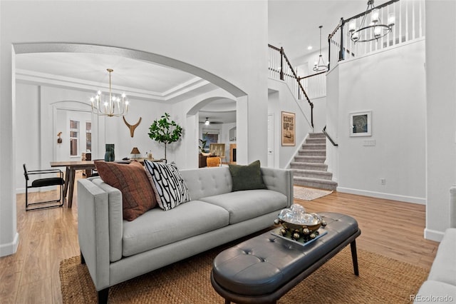 living room featuring ceiling fan with notable chandelier, light wood-type flooring, and a tray ceiling