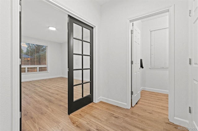 hallway with french doors and light hardwood / wood-style flooring