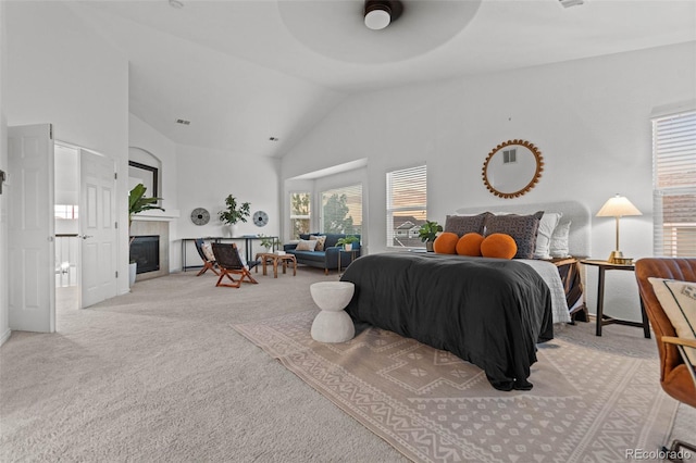 carpeted bedroom with ceiling fan, a fireplace, and vaulted ceiling