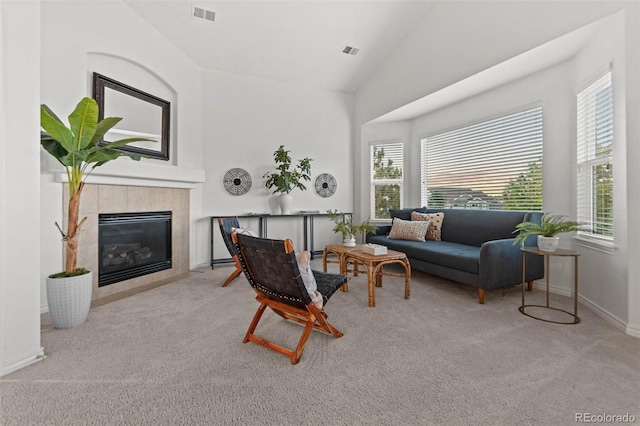 living room with light carpet, high vaulted ceiling, and a tiled fireplace