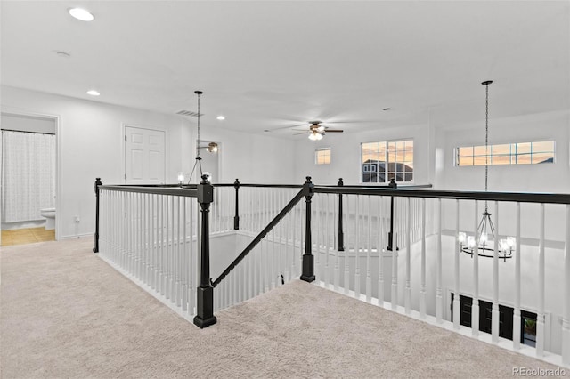 hallway featuring light colored carpet and an inviting chandelier