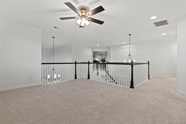 carpeted spare room with ceiling fan with notable chandelier