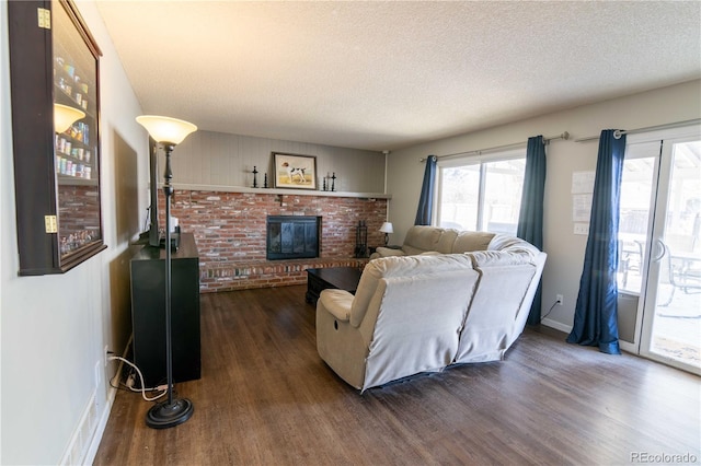 living room featuring dark wood-type flooring, a fireplace, and a textured ceiling