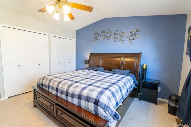 bedroom with multiple closets, vaulted ceiling, light colored carpet, and ceiling fan