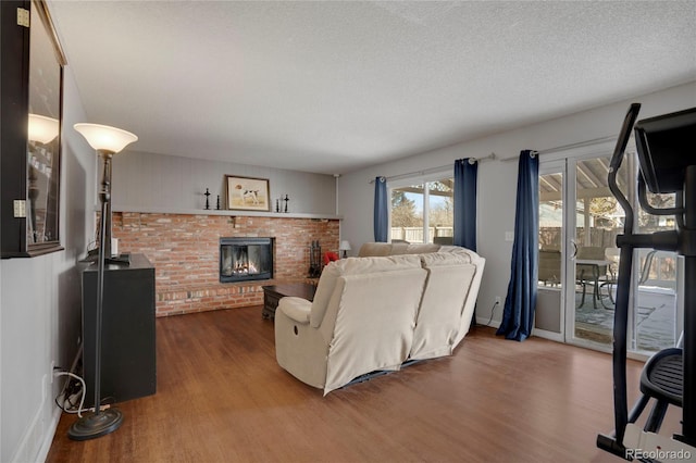 living area with a brick fireplace, a textured ceiling, baseboards, and dark wood-style flooring