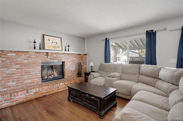 living area featuring a fireplace, a textured ceiling, and wood finished floors