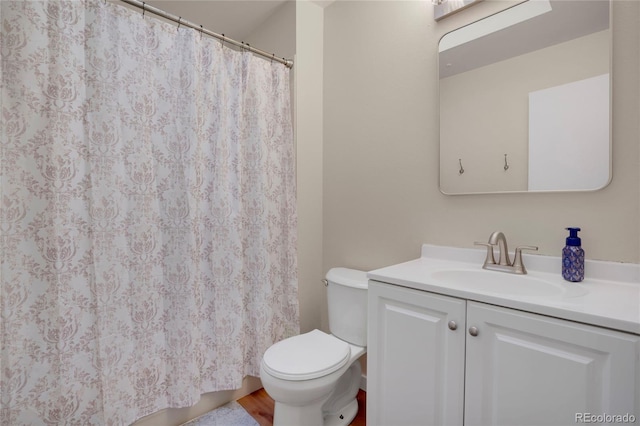 bathroom with wood finished floors, curtained shower, vanity, and toilet