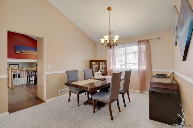 carpeted dining space with a chandelier, visible vents, high vaulted ceiling, and baseboards