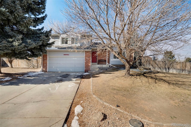 view of front facade with concrete driveway, brick siding, an attached garage, and fence