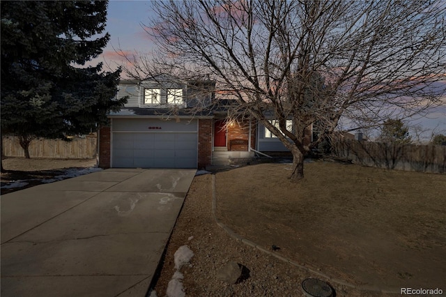 view of front of home with a garage, fence, concrete driveway, and brick siding