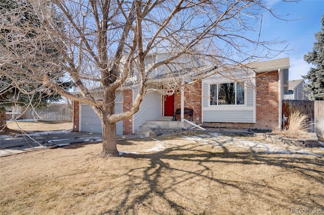 view of front of house featuring brick siding, a front yard, fence, a garage, and driveway