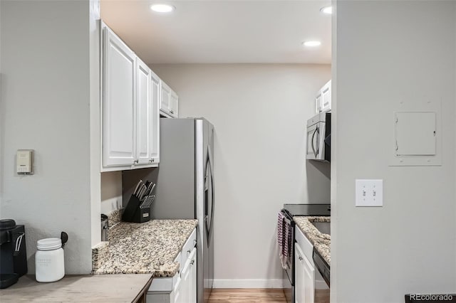 kitchen featuring white cabinetry, light hardwood / wood-style flooring, stainless steel appliances, and light stone counters