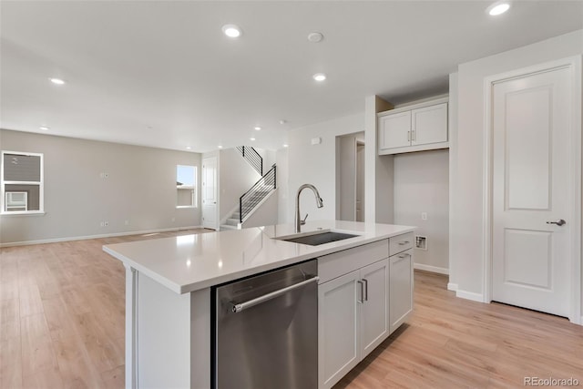 kitchen featuring a sink, light wood finished floors, light countertops, and dishwasher