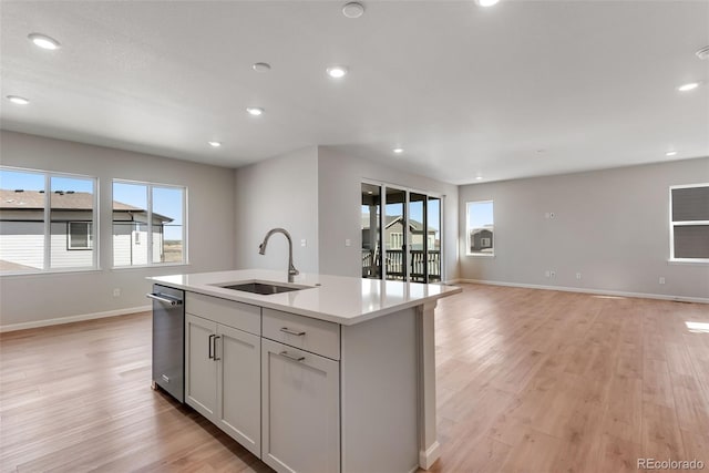 kitchen with light wood-style flooring, a sink, open floor plan, a center island with sink, and stainless steel dishwasher