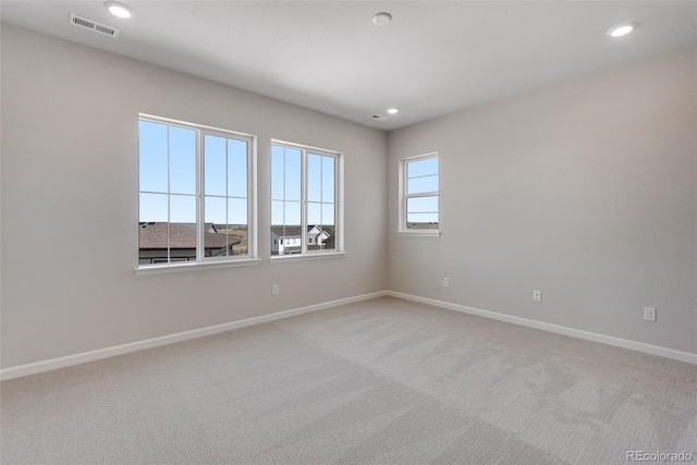 spare room featuring light colored carpet, baseboards, visible vents, and recessed lighting